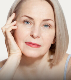 A woman with gray hair is seated comfortably on a couch, exuding a sense of calm and relaxation.