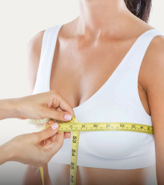 A woman uses a tape measure to accurately determine her bra size, focusing on the measurement process.