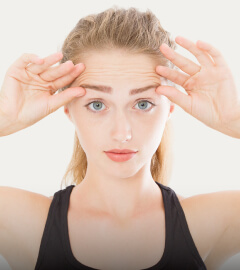 A woman is pressing her hands to her forehead, conveying a sense of contemplation or stress.