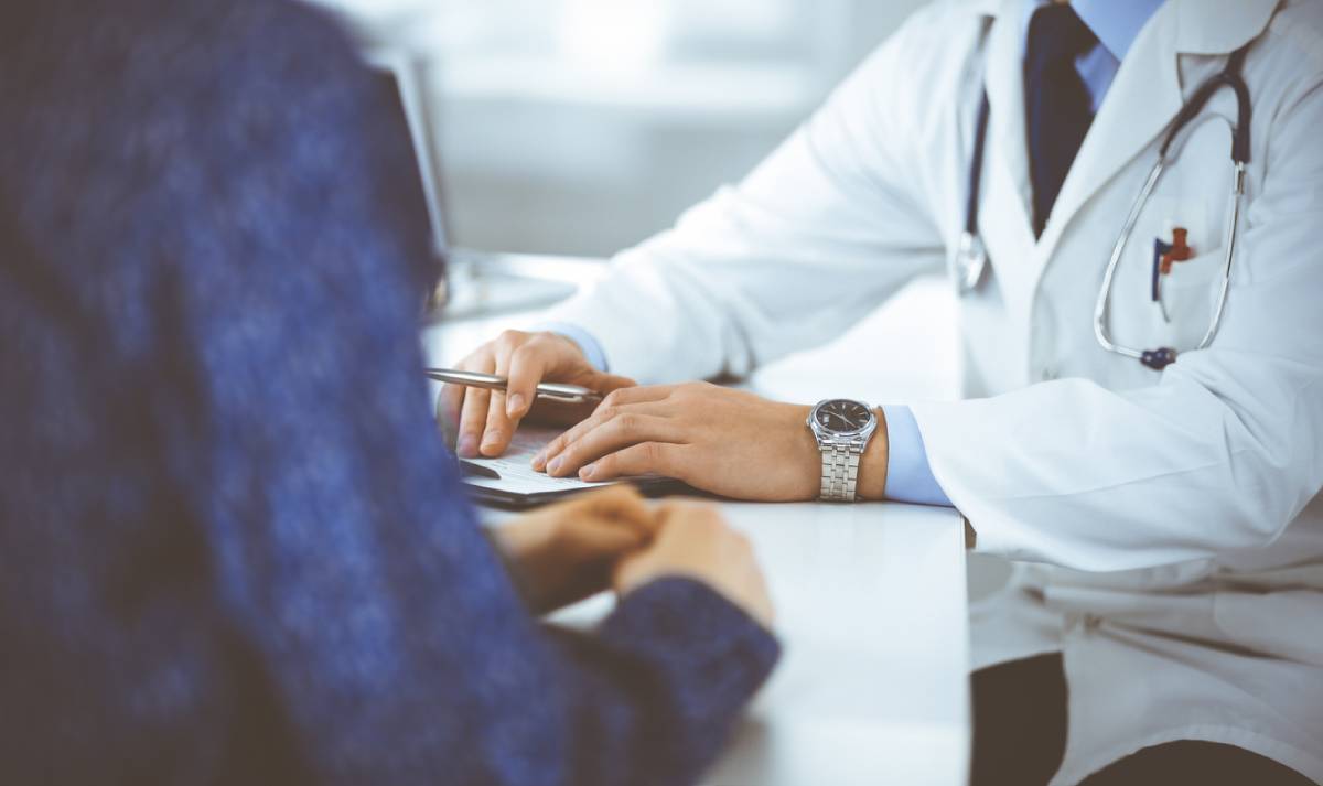 A doctor engages in conversation with a patient, discussing health concerns in a clinical setting.